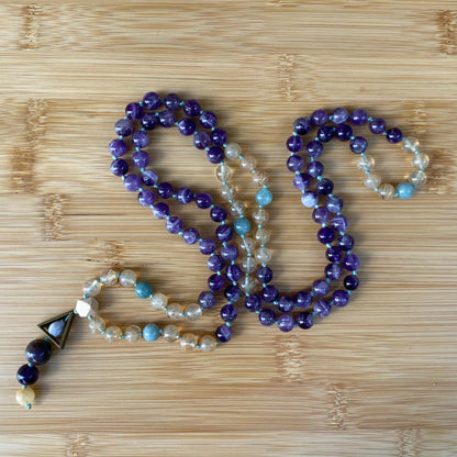 108 hand-knotted mala bead necklace featuring smooth amethyst, jade, and citrine gemstones, finished with a triangle and three-bead tassel